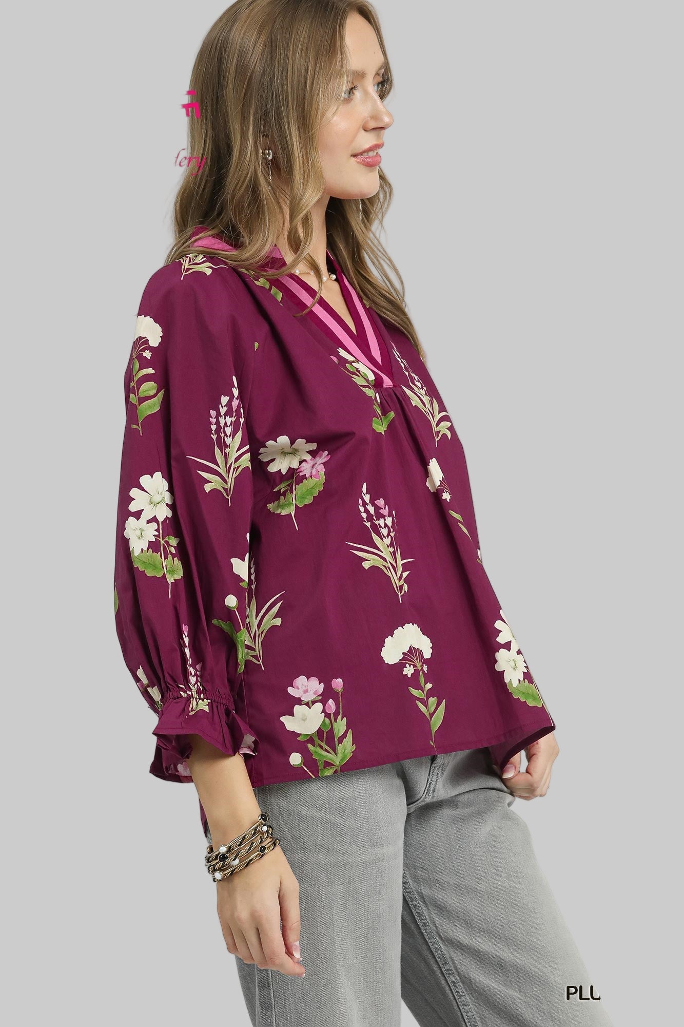 Woman wearing a plum-colored blouse with floral patterns on a white background