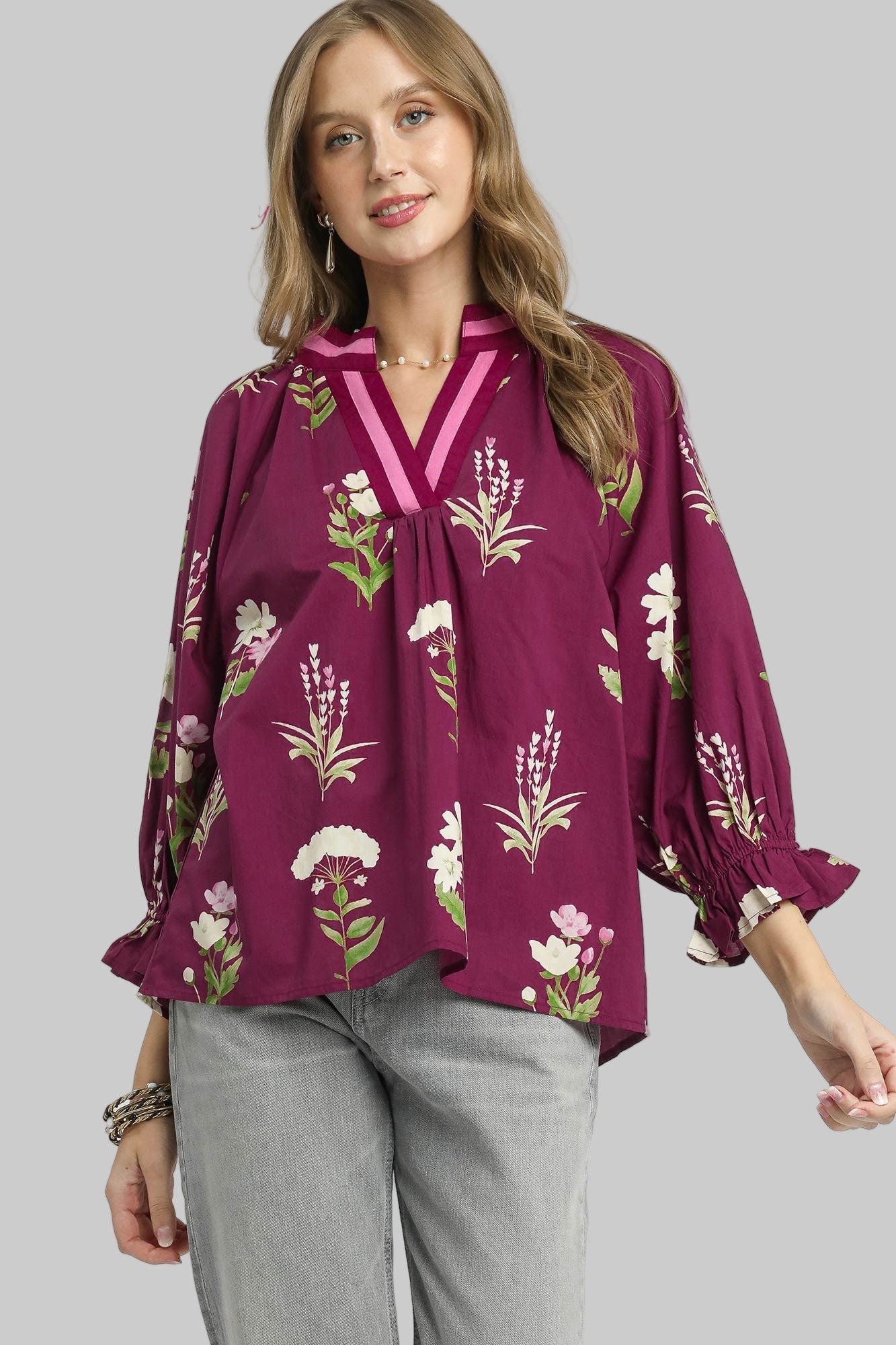 Woman wearing a purple floral blouse on a gray background